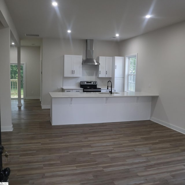 205 Magnolia St, Gaffney, SC 29340 - kitchen with wall chimney range hood, stainless steel electric range, dark wood finished floors, a sink, and white cabinets