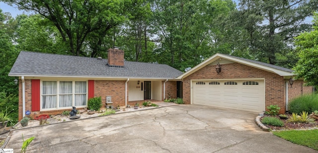223 Covington Rd, Greenville, SC 29617 - ranch-style home with concrete driveway, a chimney, brick siding, a garage, and view of scattered trees