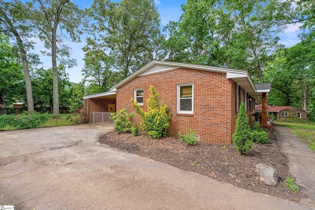 110 Sycamore Dr, Mauldin, SC 29662 - view of side of home featuring brick siding, asphalt driveway, an attached carport, and view of scattered trees