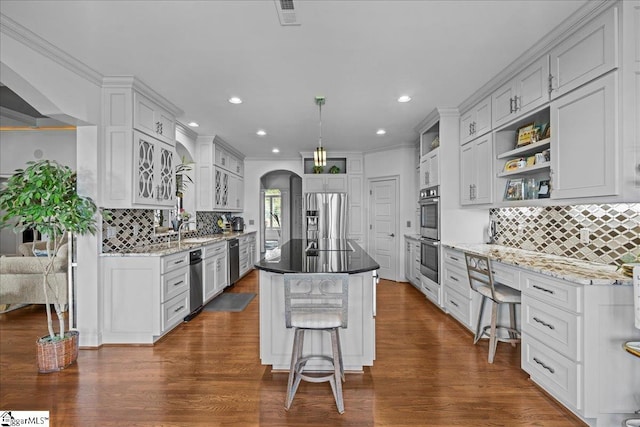 135 Neal Pointe Dr, Chesnee, SC 29323 - kitchen with appliances with stainless steel finishes, arched walkways, tasteful backsplash, a sink, and dark wood finished floors