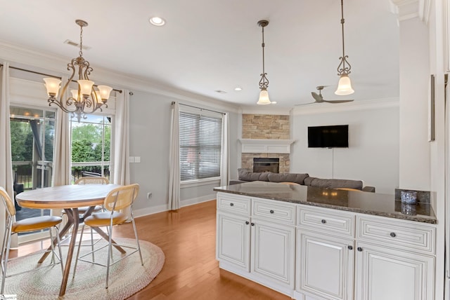 10 Croydon Way, Greenville, SC 29609 - kitchen featuring crown molding, a fireplace, light wood finished floors, a chandelier, and baseboards
