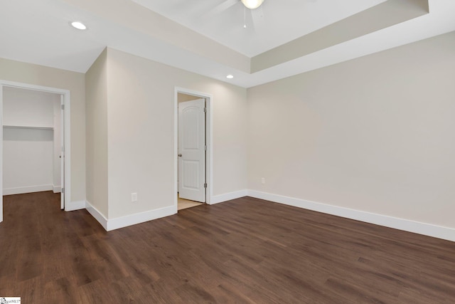 184 Sandifer Rd, Spartanburg, SC 29303 - unfurnished bedroom featuring dark wood-type flooring, baseboards, recessed lighting, a walk in closet, and a tray ceiling