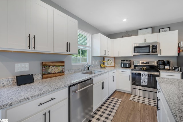 212 Ralston Dr, Greer, SC 29651 - kitchen featuring appliances with stainless steel finishes, a sink, light wood-style floors, white cabinets, and light stone countertops