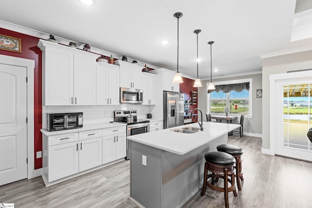 222 Blease Horton Rd, Boiling Springs, SC 29316 - kitchen with appliances with stainless steel finishes, a sink, ornamental molding, an island with sink, and light wood-style flooring
