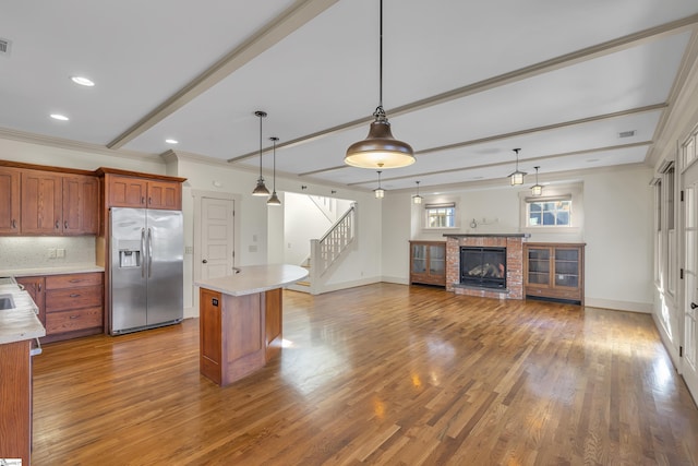 509B Townes St, Greenville, SC 29601 - kitchen featuring stainless steel refrigerator with ice dispenser, light countertops, brown cabinetry, pendant lighting, and crown molding