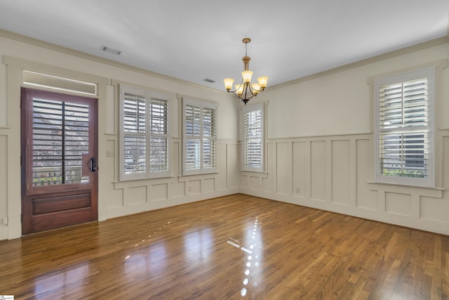 509B Townes St, Greenville, SC 29601 - empty room with a chandelier, a decorative wall, wood finished floors, a wainscoted wall, and crown molding