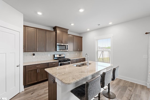 101 Hazelcroft Dr, Fountain Inn, SC 29644 - kitchen featuring appliances with stainless steel finishes, a sink, light wood-style floors, backsplash, and a center island with sink