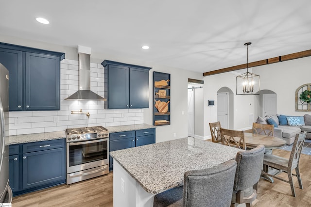 118 Perry Hill Rd, Easley, SC 29640 - kitchen featuring stainless steel range with gas stovetop, wall chimney range hood, arched walkways, blue cabinetry, and backsplash