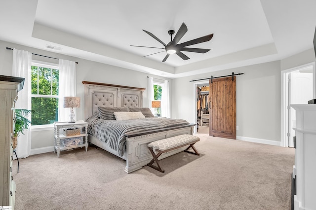 118 Perry Hill Rd, Easley, SC 29640 - bedroom featuring a tray ceiling, light colored carpet, a barn door, baseboards, and a spacious closet