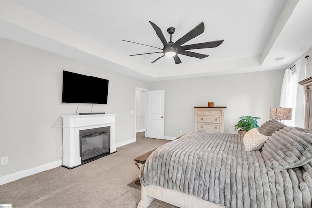 118 Perry Hill Rd, Easley, SC 29640 - carpeted bedroom with a tray ceiling, a glass covered fireplace, baseboards, and a ceiling fan