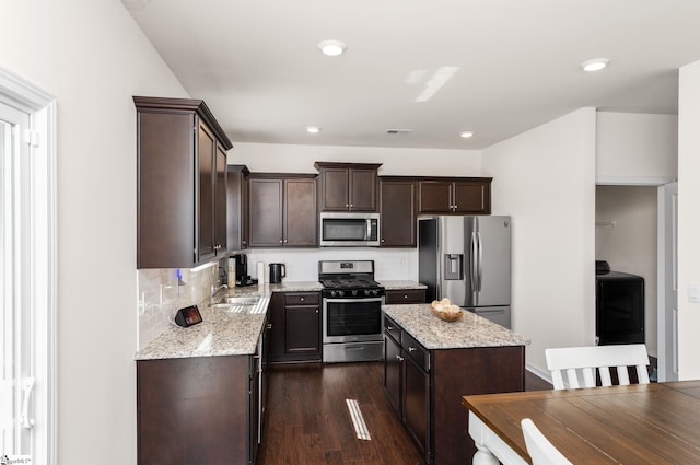 912 Brynderwen Pl, Lyman, SC 29365 - kitchen featuring appliances with stainless steel finishes, dark brown cabinetry, a center island, washer / dryer, and tasteful backsplash