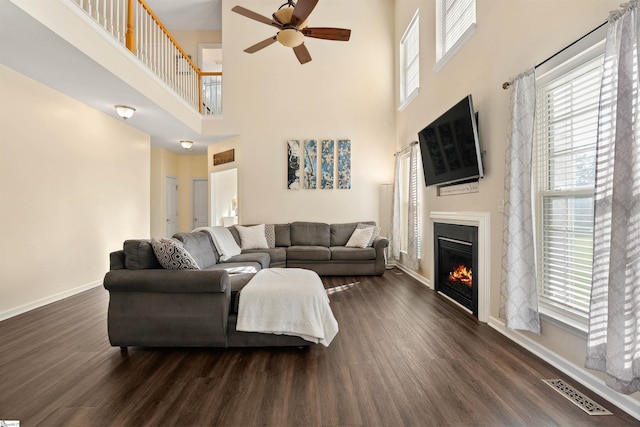 105 Franklin Meadow Way, Greer, SC 29651 - living area with a ceiling fan, a towering ceiling, dark wood-type flooring, baseboards, and a glass covered fireplace