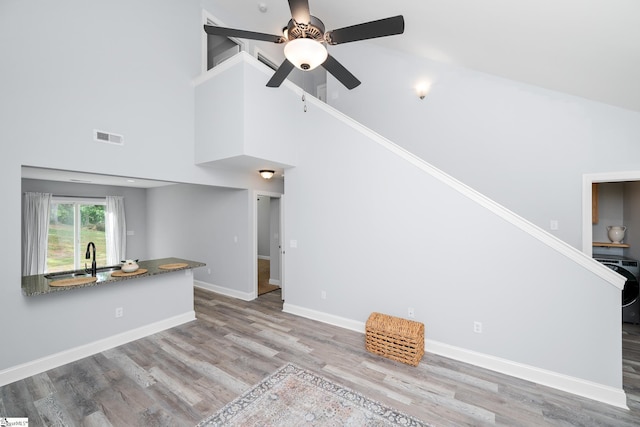 216 Country Gln, Pelzer, SC 29669 - unfurnished living room featuring a sink, a ceiling fan, wood finished floors, a towering ceiling, and baseboards
