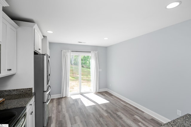 216 Country Gln, Pelzer, SC 29669 - kitchen featuring appliances with stainless steel finishes, wood finished floors, white cabinets, dark stone countertops, and baseboards
