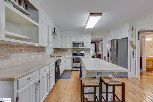 101 N Lady Slipper Ln, Greer, SC 29650 - kitchen featuring stainless steel appliances, a sink, open shelves, light wood finished floors, and ornamental molding