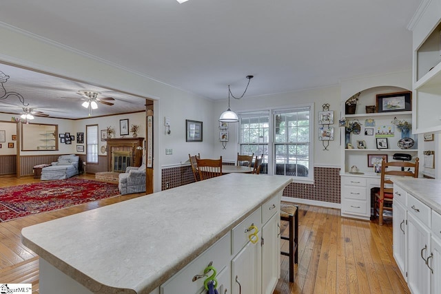101 N Lady Slipper Ln, Greer, SC 29650 - kitchen with light wood-style flooring, white cabinetry, a brick fireplace, light countertops, and wainscoting