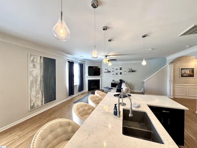 200 Odie Dr, Simpsonville, SC 29681 - kitchen featuring a fireplace, ornamental molding, a sink, decorative columns, and arched walkways