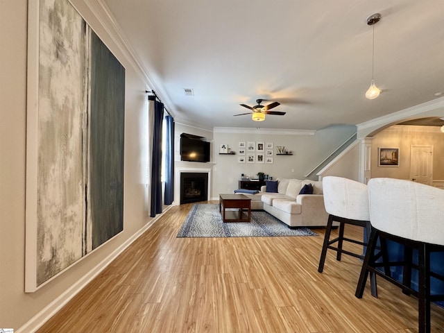 200 Odie Dr, Simpsonville, SC 29681 - living room featuring arched walkways, a ceiling fan, wood finished floors, crown molding, and a fireplace