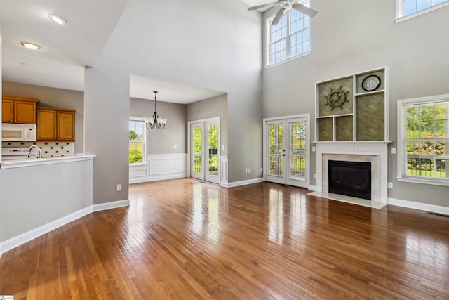 1073 Corie Crest Dr, Boiling Springs, SC 29316 - unfurnished living room featuring a chandelier, ceiling fan, hardwood / wood-style floors, a high ceiling, and a fireplace with flush hearth
