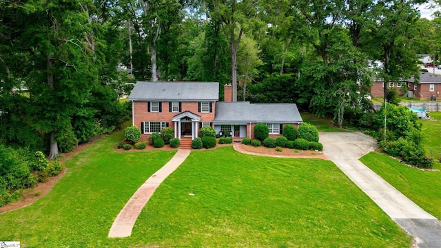 302 Spruce St, Clinton, SC 29325 - colonial home featuring concrete driveway, brick siding, a chimney, and a front lawn