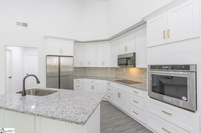 1008 Tribble St, Anderson, SC 29625 - kitchen with stainless steel appliances, a sink, white cabinetry, a high ceiling, and decorative backsplash
