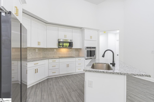 1008 Tribble St, Anderson, SC 29625 - kitchen with stainless steel appliances, a sink, white cabinetry, decorative backsplash, and light wood finished floors