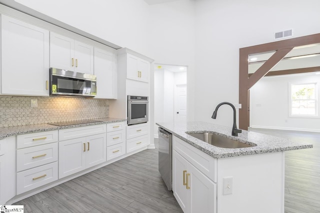 1008 Tribble St, Anderson, SC 29625 - kitchen with stainless steel appliances, a sink, white cabinets, light wood finished floors, and backsplash