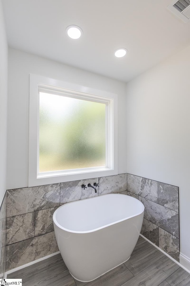 1008 Tribble St, Anderson, SC 29625 - full bathroom featuring tile walls, a soaking tub, wainscoting, wood finished floors, and recessed lighting