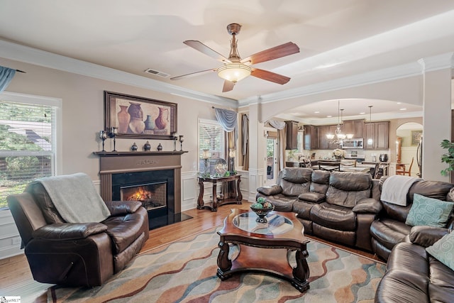 100 Claiborne Rd, Piedmont, SC 29673 - living area with arched walkways, crown molding, light wood-style flooring, ceiling fan, and a warm lit fireplace