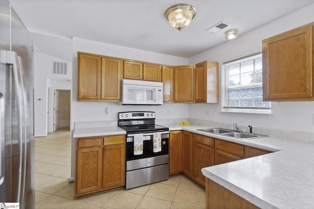 103 Berry Ct, Belton, SC 29627 - kitchen featuring appliances with stainless steel finishes, a sink, light countertops, light tile patterned floors, and brown cabinets