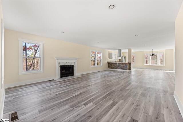 183 Wittmore Ln, Cleveland, SC 29635 - unfurnished living room with a chandelier, a high end fireplace, light wood-type flooring, and baseboards