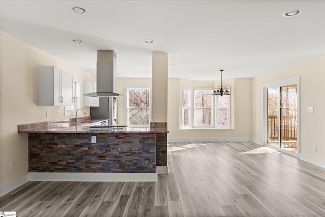 183 Wittmore Ln, Cleveland, SC 29635 - kitchen featuring island range hood, light wood-style floors, stone countertops, a sink, and healthy amount of natural light