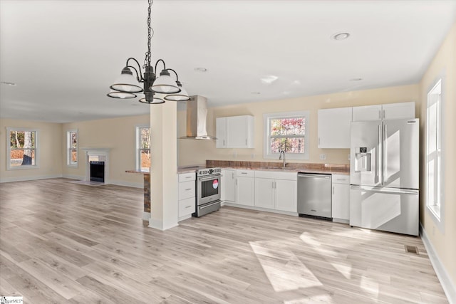 183 Wittmore Ln, Cleveland, SC 29635 - kitchen featuring stainless steel appliances, wall chimney exhaust hood, a chandelier, white cabinetry, and a sink