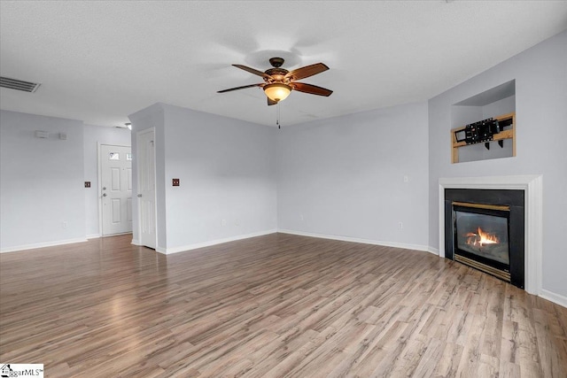 316 Stillwater Dr, Simpsonville, SC 29681 - unfurnished living room with wood finished floors, ceiling fan, a glass covered fireplace, and baseboards