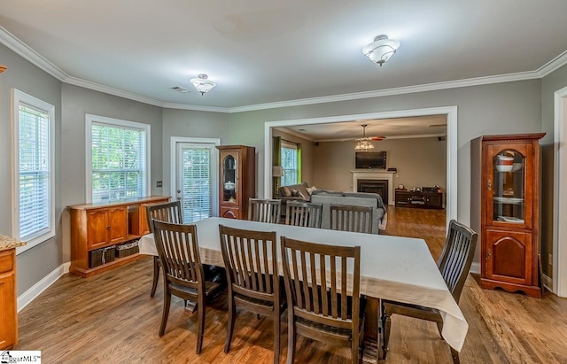 414 Mayburgh Ct, Spartanburg, SC 29301 - dining room featuring crown molding, light wood-style flooring, a fireplace, and baseboards