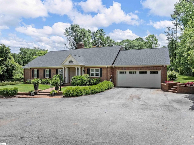 1076 Woodburn Rd, Spartanburg, SC 29302 - neoclassical / greek revival house with asphalt driveway, brick siding, an attached garage, and a chimney