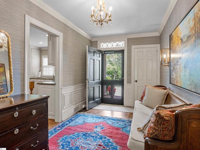 1076 Woodburn Rd, Spartanburg, SC 29302 - foyer entrance with wallpapered walls, a chandelier, light wood-style flooring, a wainscoted wall, and ornamental molding