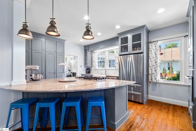 201 W Arlington Ave, Greer, SC 29650 - kitchen featuring appliances with stainless steel finishes, a peninsula, light stone countertops, glass insert cabinets, and light wood-style floors