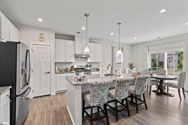 311 Sandusky Ln, Simpsonville, SC 29680 - kitchen with appliances with stainless steel finishes, under cabinet range hood, light wood-style flooring, a kitchen bar, and backsplash