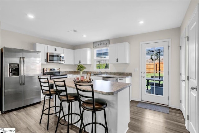 275 Ralston Rd, Greer, SC 29651 - kitchen with stainless steel appliances, a kitchen breakfast bar, light wood-type flooring, white cabinets, and a center island