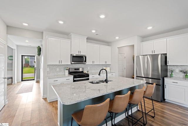 1019 Appalachian Dr, Moore, SC 29369 - kitchen featuring appliances with stainless steel finishes, a sink, decorative backsplash, an island with sink, and white cabinets