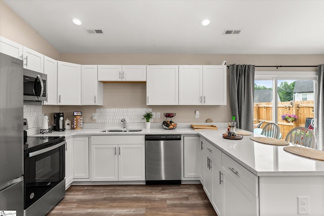 101 Sunrise Rd, Spartanburg, SC 29302 - kitchen with appliances with stainless steel finishes, a peninsula, a sink, white cabinets, and dark wood-type flooring