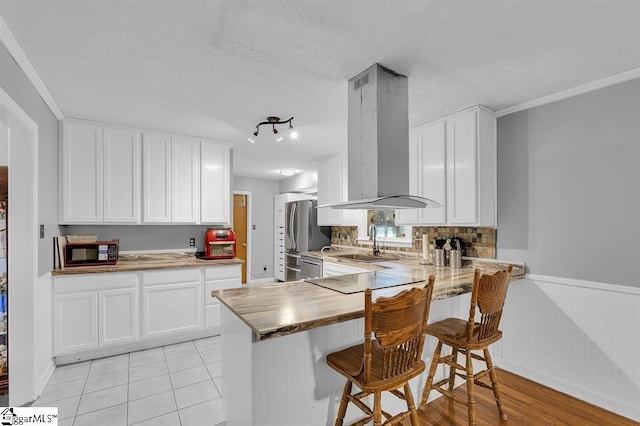 469 Royal Oak Dr, Spartanburg, SC 29302 - kitchen featuring island exhaust hood, a sink, white cabinets, wainscoting, and a kitchen bar