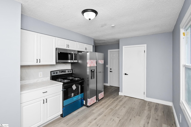 127 Chelsea St, Moore, SC 29369 - kitchen with stainless steel appliances, light wood finished floors, white cabinets, light countertops, and baseboards
