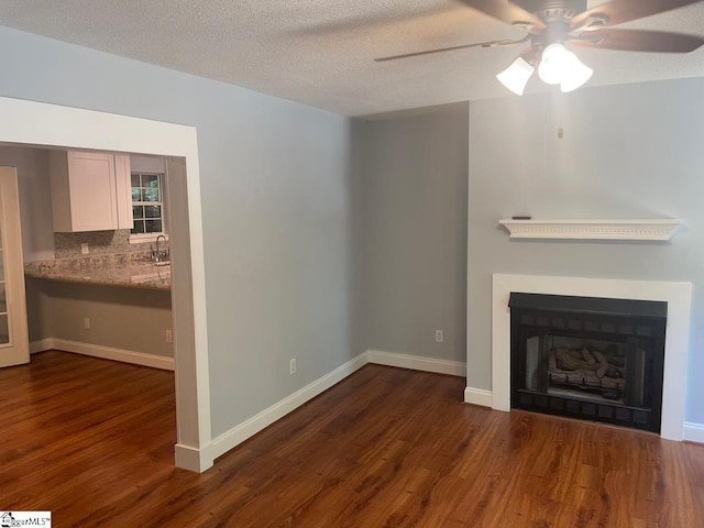 1002 Still Holllow Ln, Taylors, SC 29687 - unfurnished living room with dark wood finished floors, a ceiling fan, a fireplace, a sink, and a textured ceiling