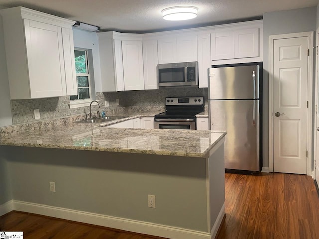 1002 Still Holllow Ln, Taylors, SC 29687 - kitchen with appliances with stainless steel finishes, light stone countertops, white cabinets, a sink, and a peninsula