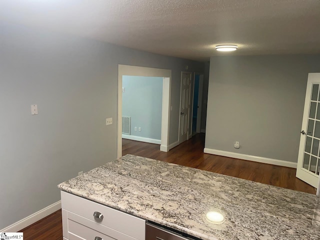 1002 Still Holllow Ln, Taylors, SC 29687 - kitchen featuring dark wood-style floors, baseboards, light stone counters, white cabinets, and a textured ceiling