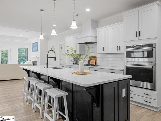 115 Harbor Master Ln, Taylors, SC 29687 - kitchen with stainless steel appliances, a sink, premium range hood, backsplash, and a kitchen island with sink