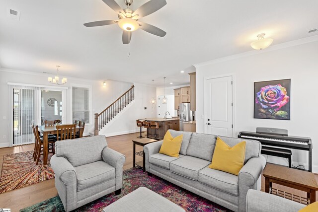 1 Winding Rock Rd, Simpsonville, SC 29680 - living area featuring a chandelier, light wood finished floors, ornamental molding, stairway, and a ceiling fan