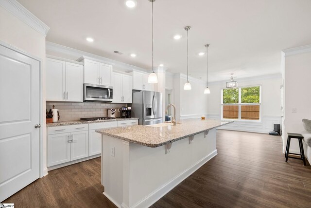 305 Kellen Ct, Duncan, SC 29334 - kitchen featuring appliances with stainless steel finishes, crown molding, dark wood-style floors, white cabinets, and a kitchen bar
